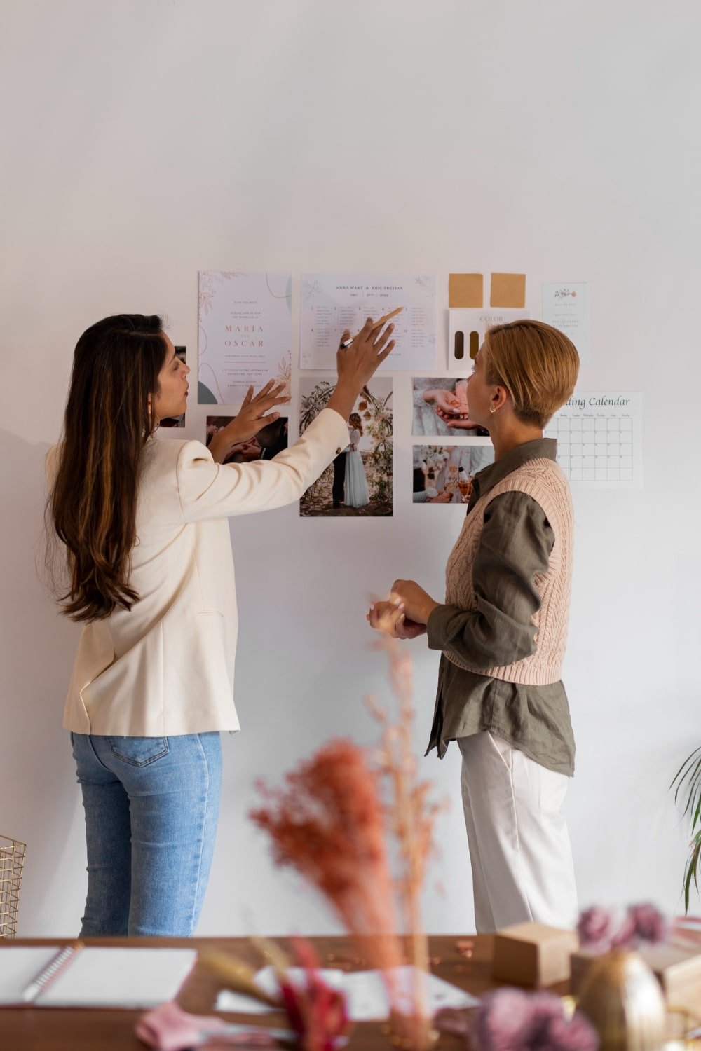 Deux femmes discutant et planifiant sur un mur rempli de photos et de notes.