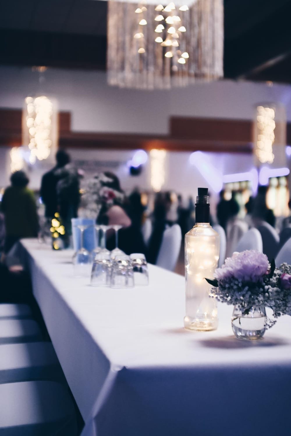 Salle de réception élégamment décorée avec une table dressée et des décorations lumineuses.