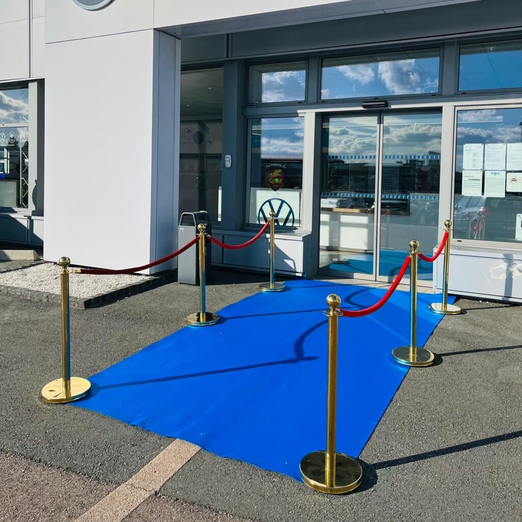 Image de la façade d'un showroom Volkswagen avec un tapis rouge et une corde de velours.