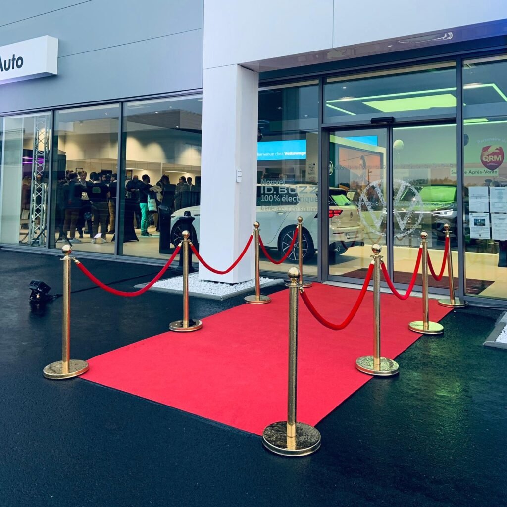 Entrée de showroom Volkswagen avec tapis rouge et cordes de velours dorées.